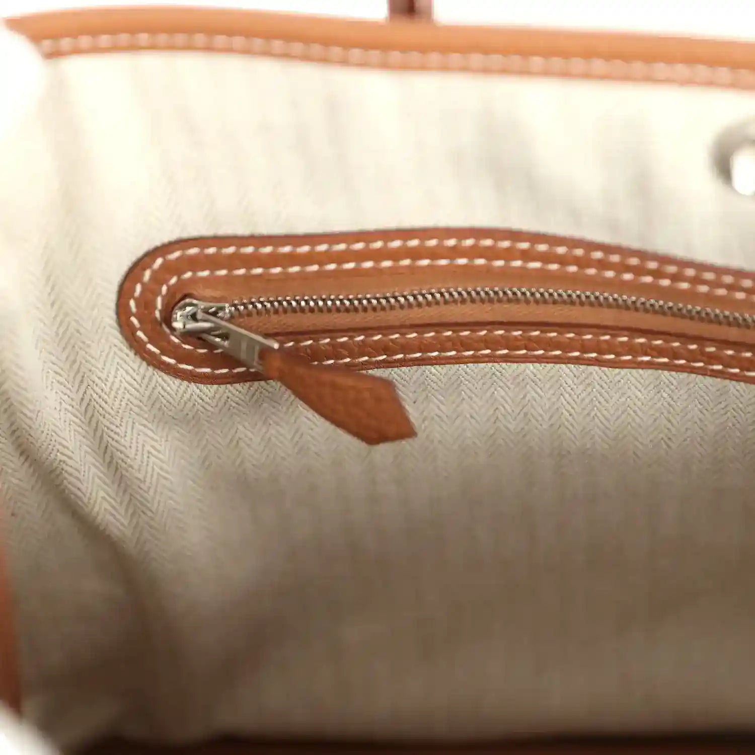 Tote interior with zipper pull and brown leather trim on the pocket
