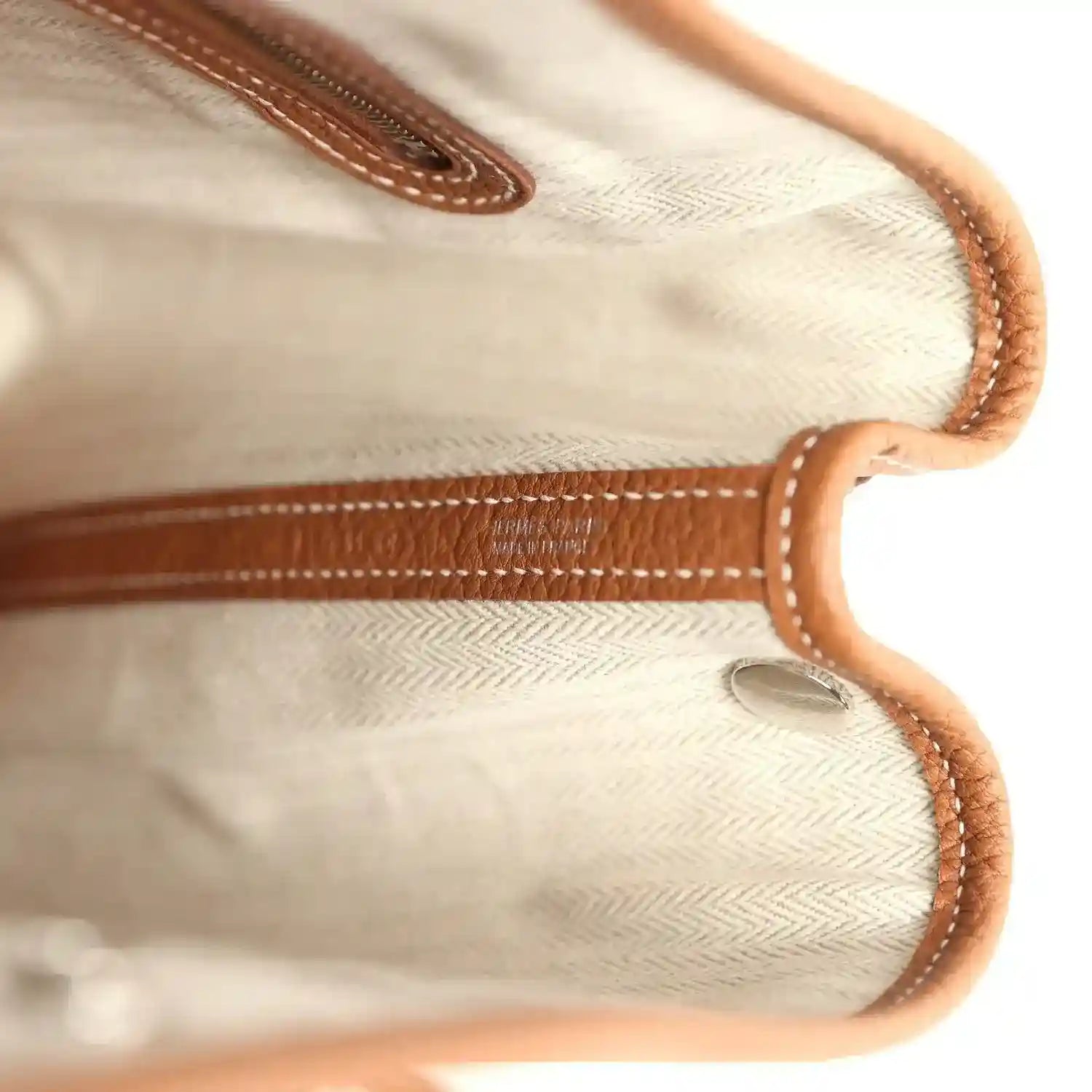 Light interior lining with brown leather handle attachment and stitched edges