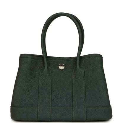 Dark green leather tote handbag with top handles and round front metal clasp