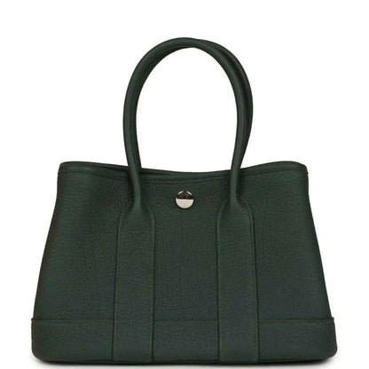 Dark green leather tote handbag with top handles and round front metal clasp