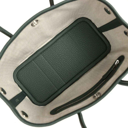 Green leather pocket insert inside a tote, set against light fabric lining