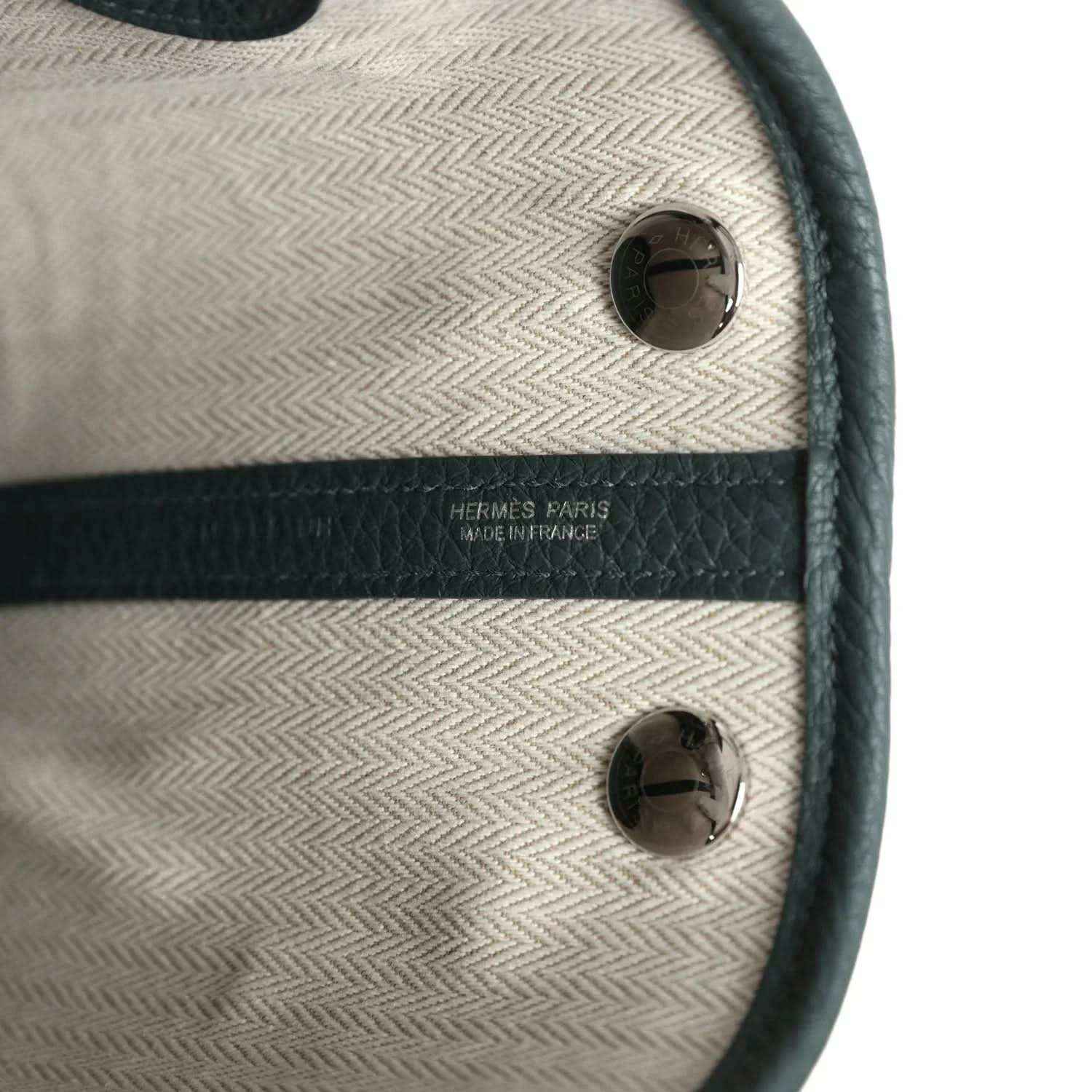 Tote interior label area with light lining, dark leather trim, and metal snaps