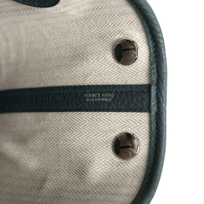 Tote interior label area with light lining, dark leather trim, and metal snaps