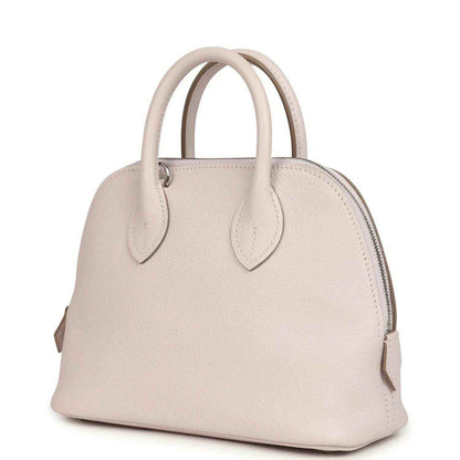 Mauve mini handbag with front yoke, zipper top, and two leather handles