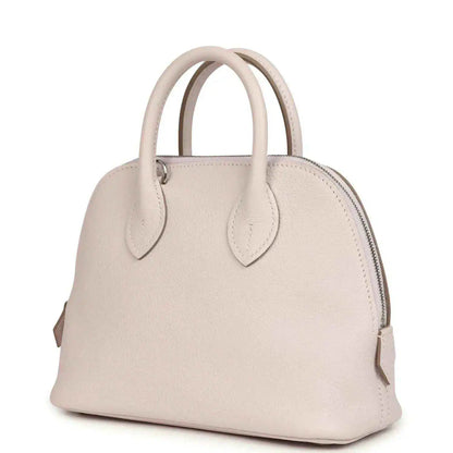 Mauve mini handbag with front yoke, zipper top, and two leather handles