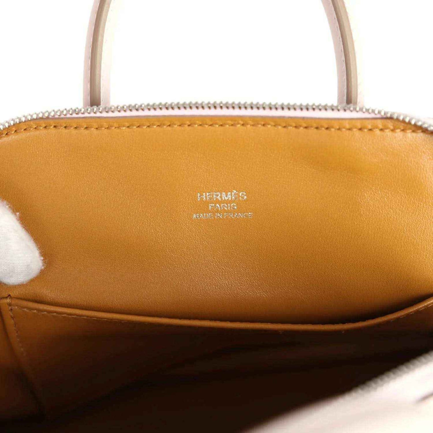 Tan leather interior of mini handbag with logo stamp under the zip