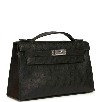 Black ostrich leather Kelly clutch with top handle, front flap and silver-tone clasp