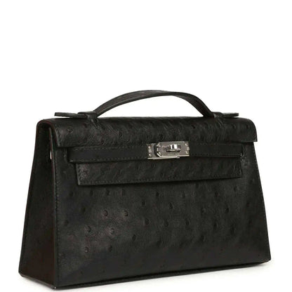 Black ostrich leather Kelly clutch with top handle, front flap and silver-tone clasp