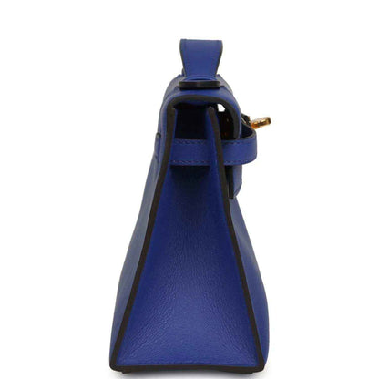 Electric blue leather pochette with side strap and gold hardware near top opening
