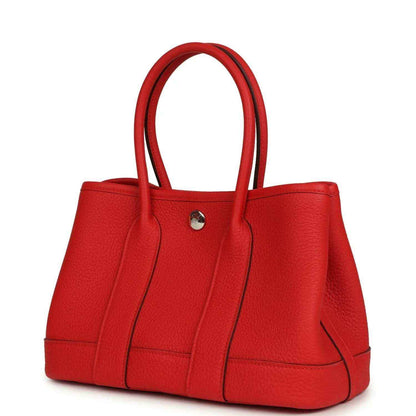 Red leather tote bag with top handles and curved side gussets