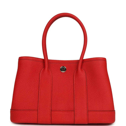 Red togo leather tote bag front view with top handles and metal snap closure