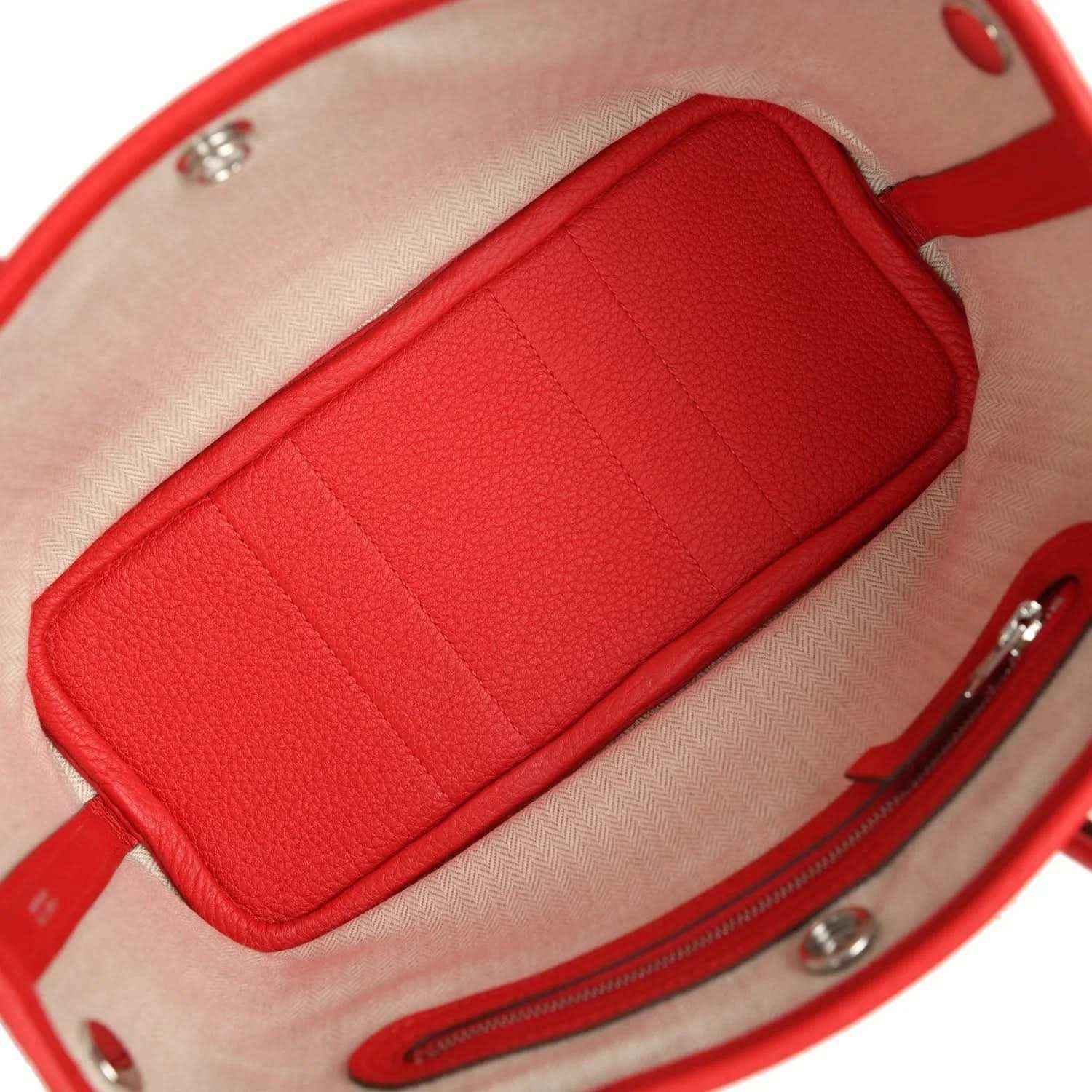 Red leather tote bag side view with top handles and rounded bucket-shaped body