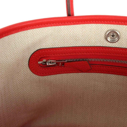 Red fabric-lined interior of leather tote with zipper and metal snap button