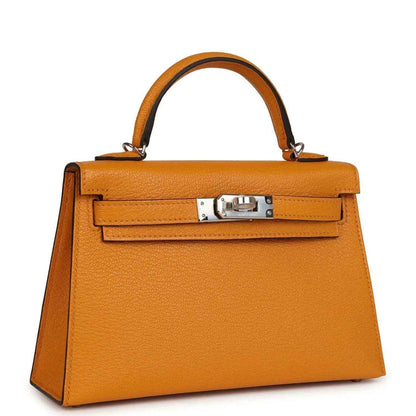 Mustard yellow leather top-handle handbag with structured front flap and silver-tone clasp