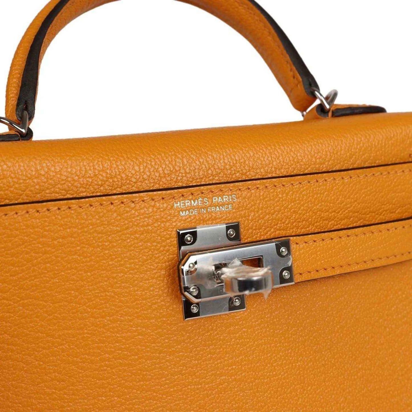 Mustard yellow leather handbag close-up of HERMES PARIS clasp plate and engraved hardware