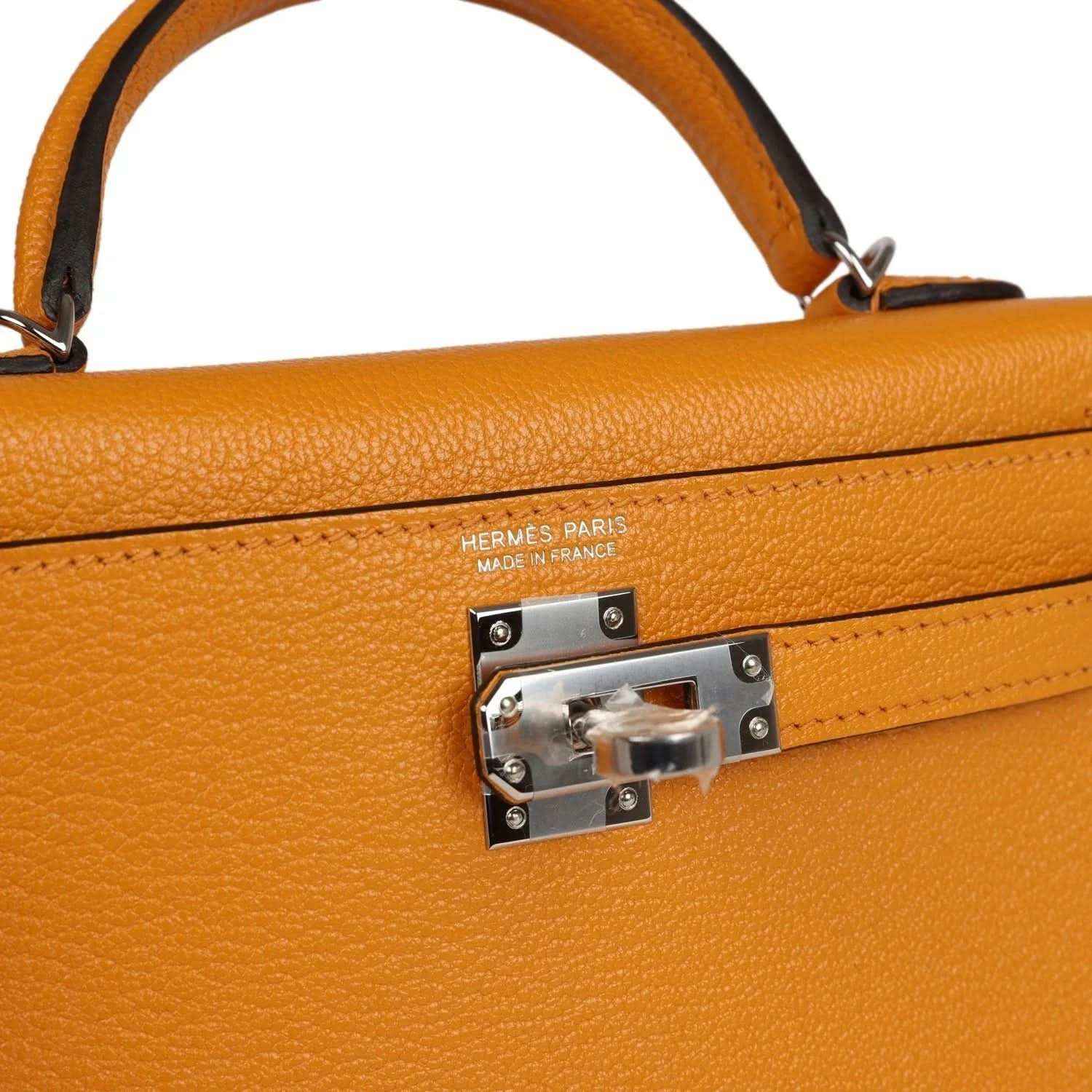 Mustard yellow leather handbag close-up of HERMES PARIS clasp plate and engraved hardware