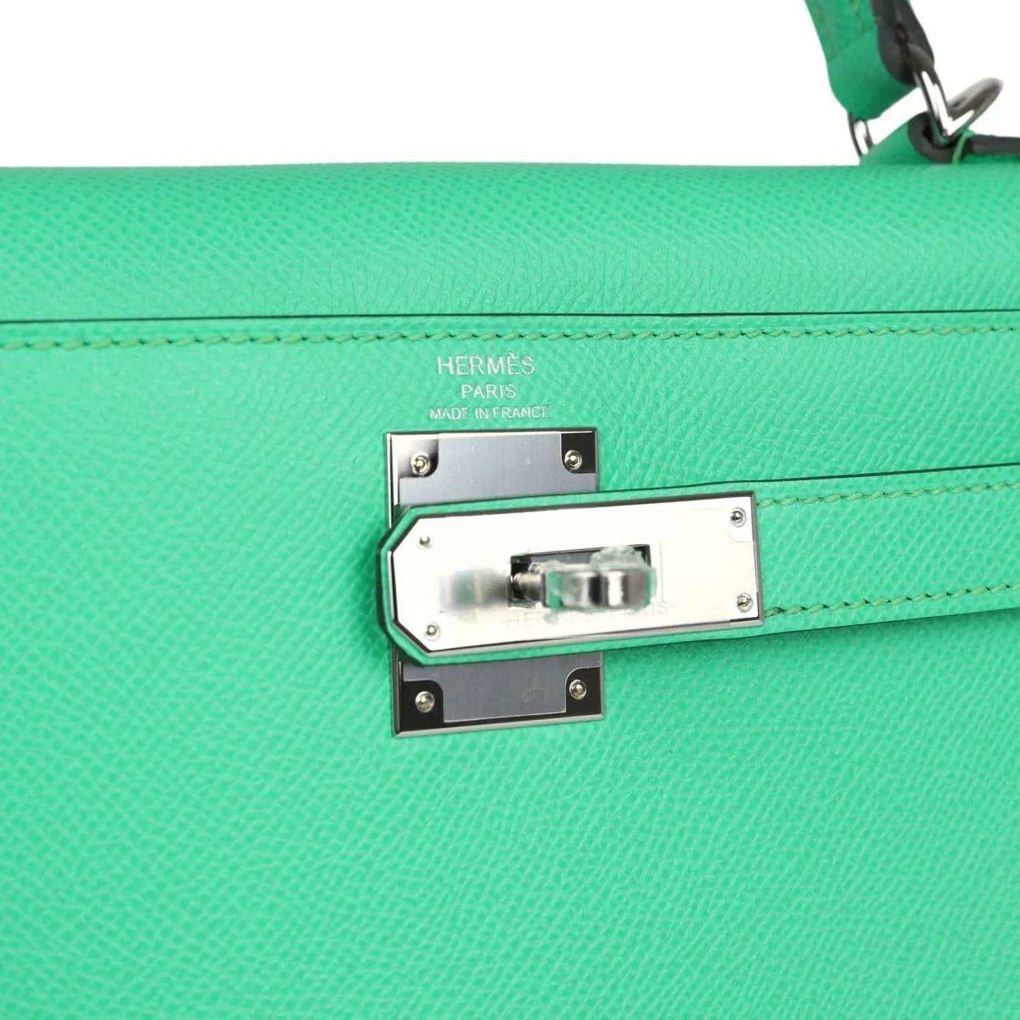 Silver clasp plate with Hermes Paris stamping on green leather handbag flap