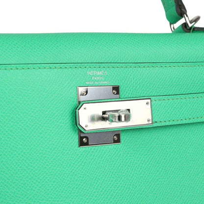 Silver clasp plate with Hermes Paris stamping on green leather handbag flap