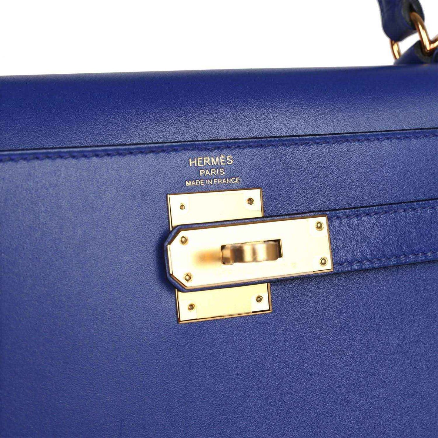 Hermes lock hardware on blue leather handbag with gold-tone plaque