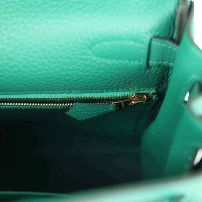 Green leather handbag interior with side zipper track and gold-tone pull hardware