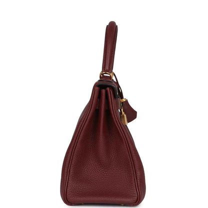 Red leather Hermès Kelly Retourne handbag with top handle and hanging strap detail