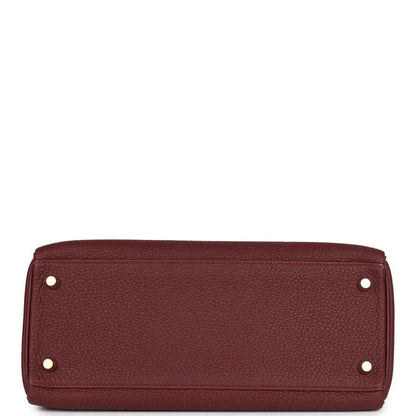 Red leather Hermès Kelly Retourne handbag base with metal feet and rivets