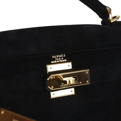 Hermès gold front lock hardware with engraved logos on black suede bag