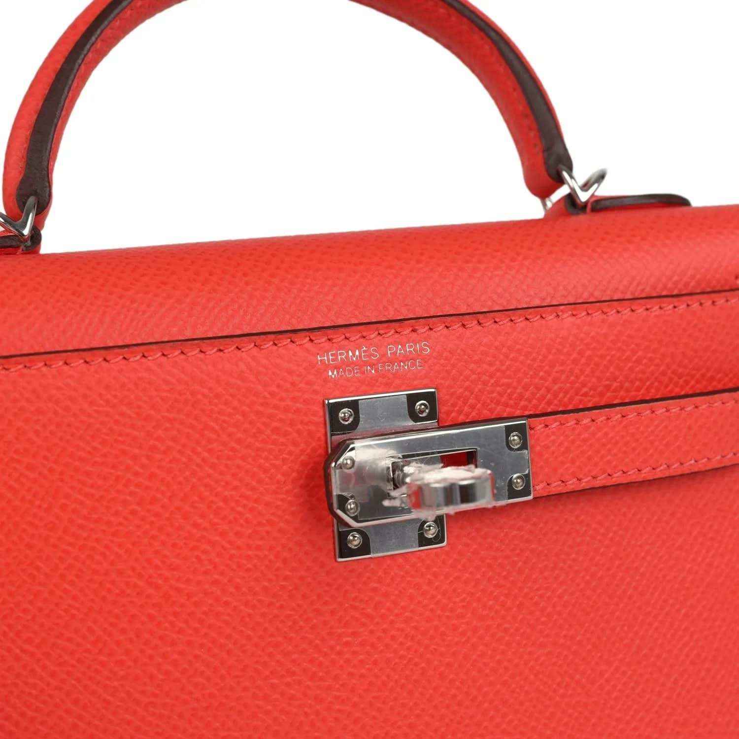Hermes Kelly Sellier 20 close-up: orange-red flap lock with engraved metal clasp