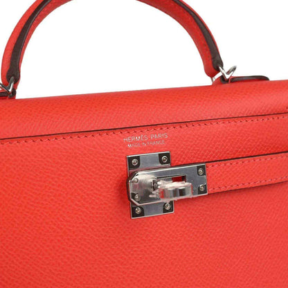 Hermes Kelly Sellier 20 close-up: orange-red flap lock with engraved metal clasp