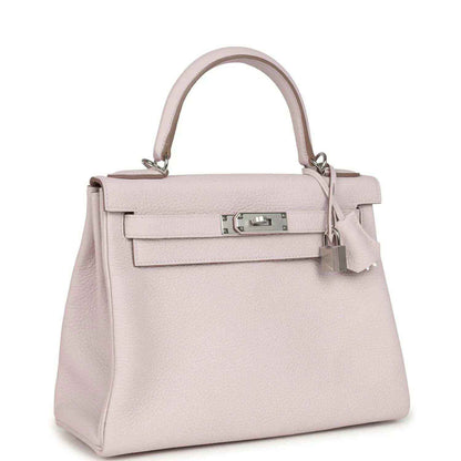 Light mauve leather handbag with structured front flap and top handle, silver-tone clasp