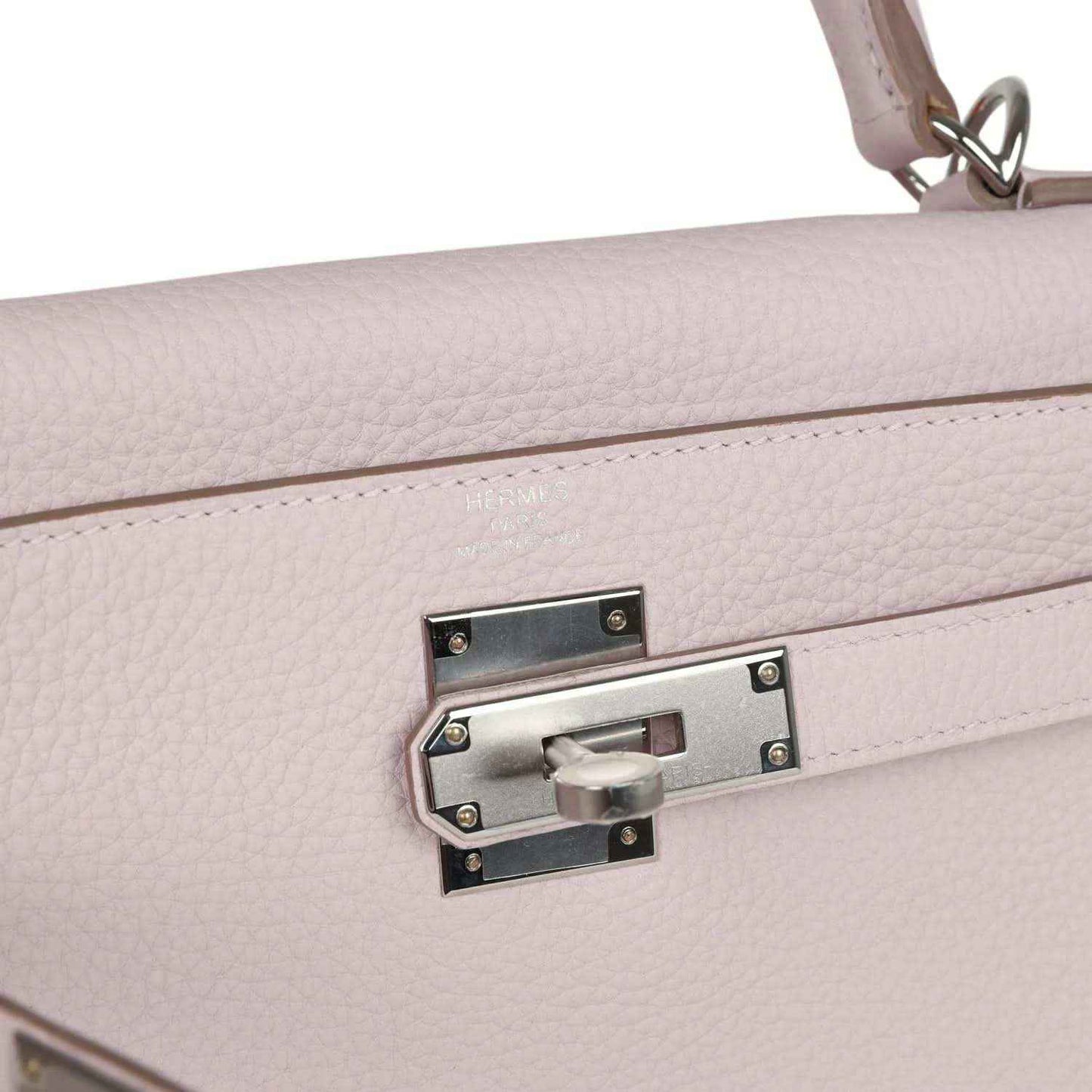Light mauve leather handbag close-up of front lock plate and silver-tone hardware