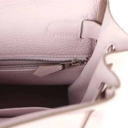 Light mauve leather handbag interior close-up with zipper track and leather divider