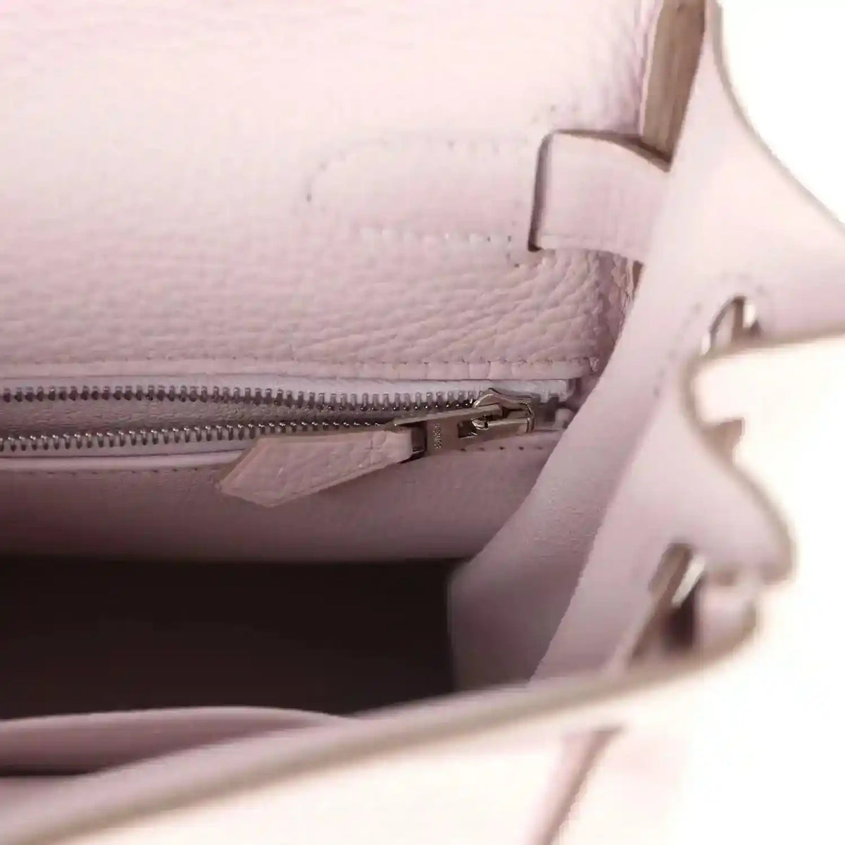 Light mauve leather handbag interior close-up with zipper track and leather divider