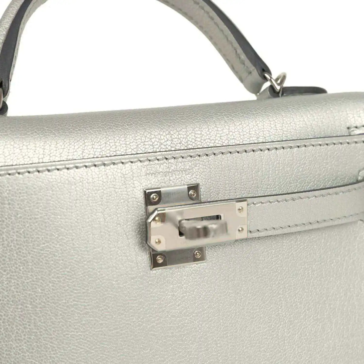 Front turn-lock hardware on light gray mini handbag with top handle strap