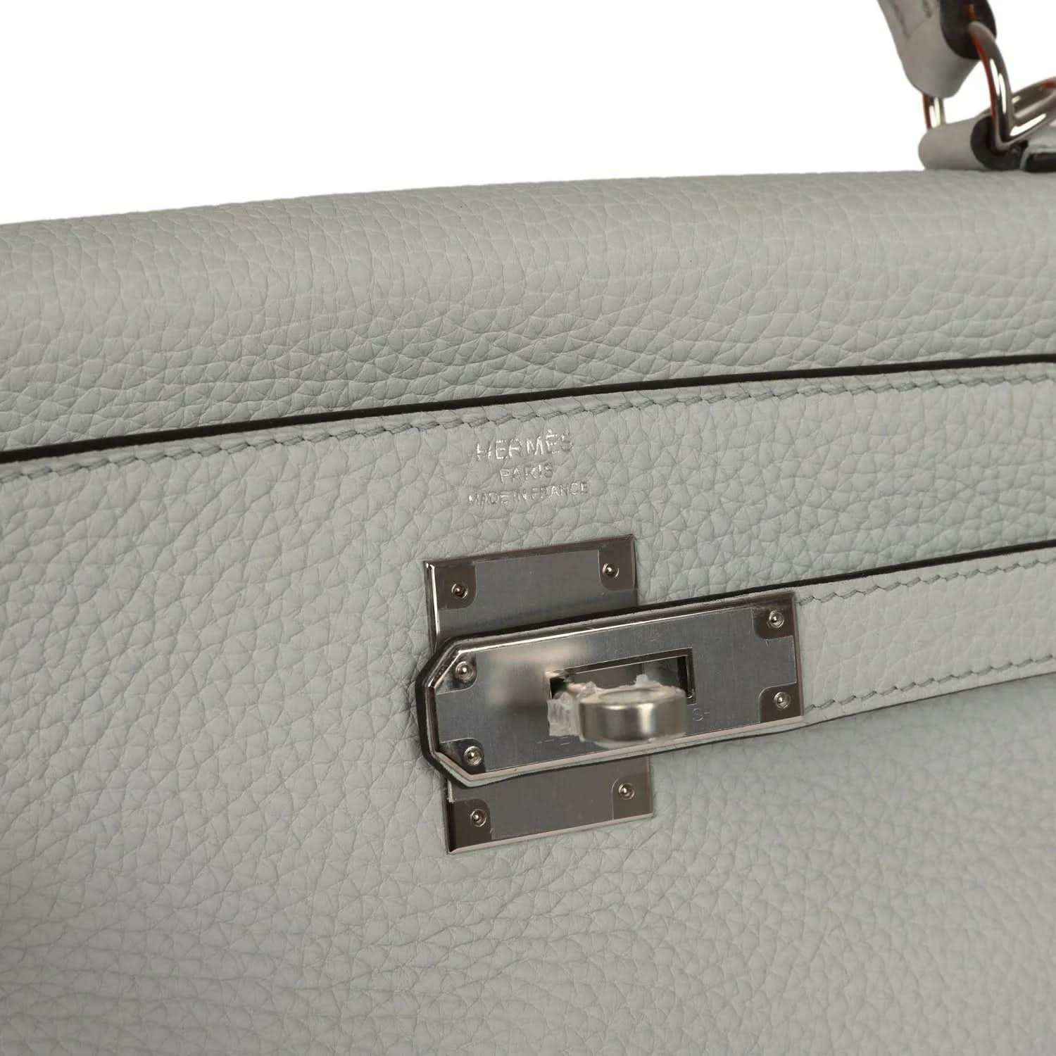Light blue leather bag with silver-tone turn-lock clasp hardware on front flap.