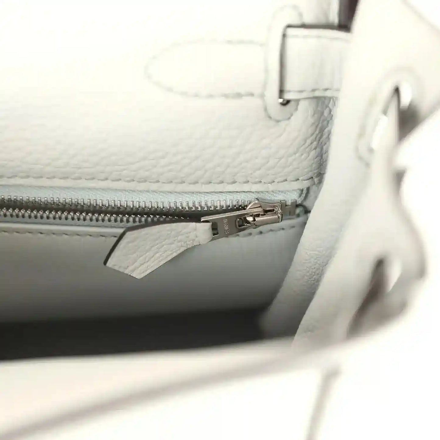 Light blue leather bag interior with zipper pocket and metal zipper pull.