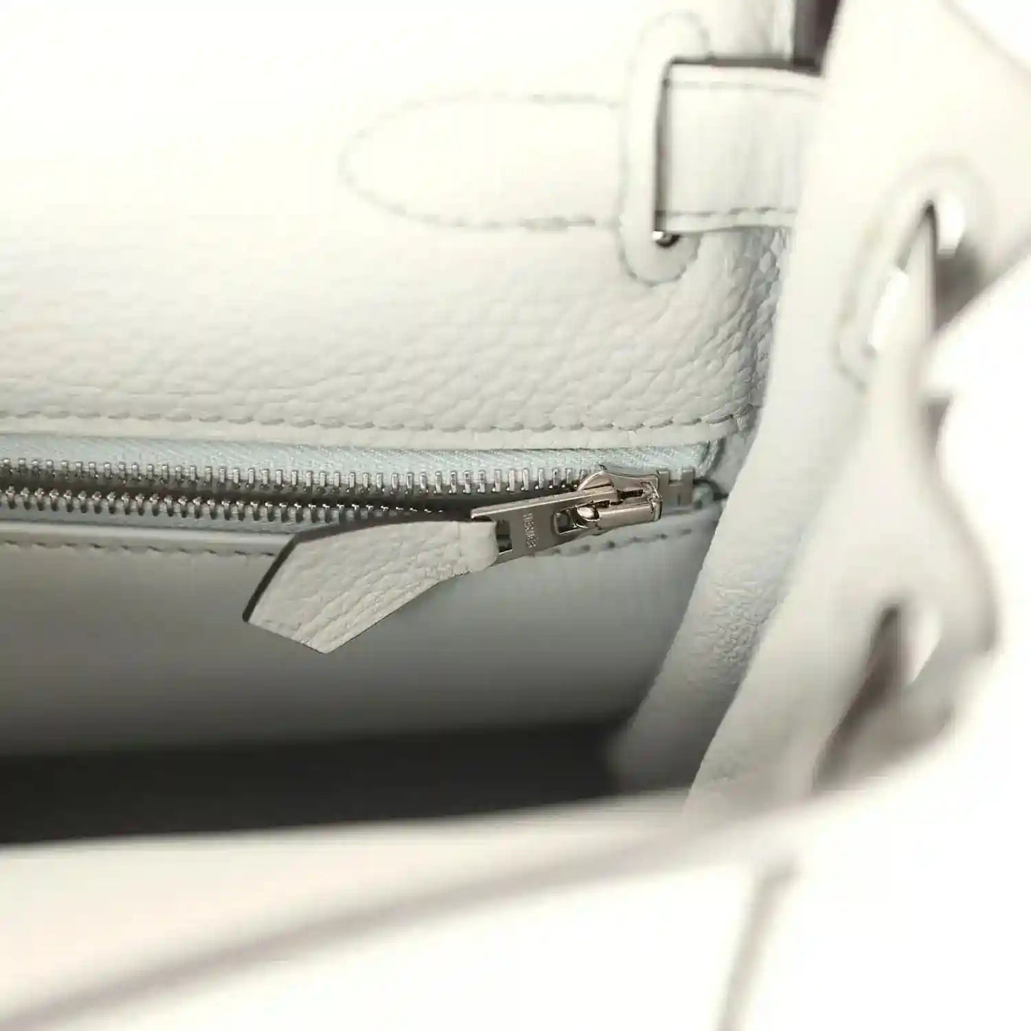Light blue leather bag interior with zipper pocket and metal zipper pull.