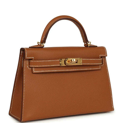 Mini leather handbag with top handle and gold front clasp, tan textured finish