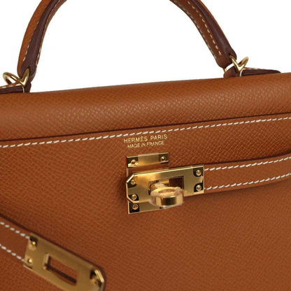 Tan leather handbag close-up with gold clasp and HERMES PARIS stamp