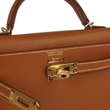 Tan leather handbag close-up with gold clasp and HERMES PARIS stamp