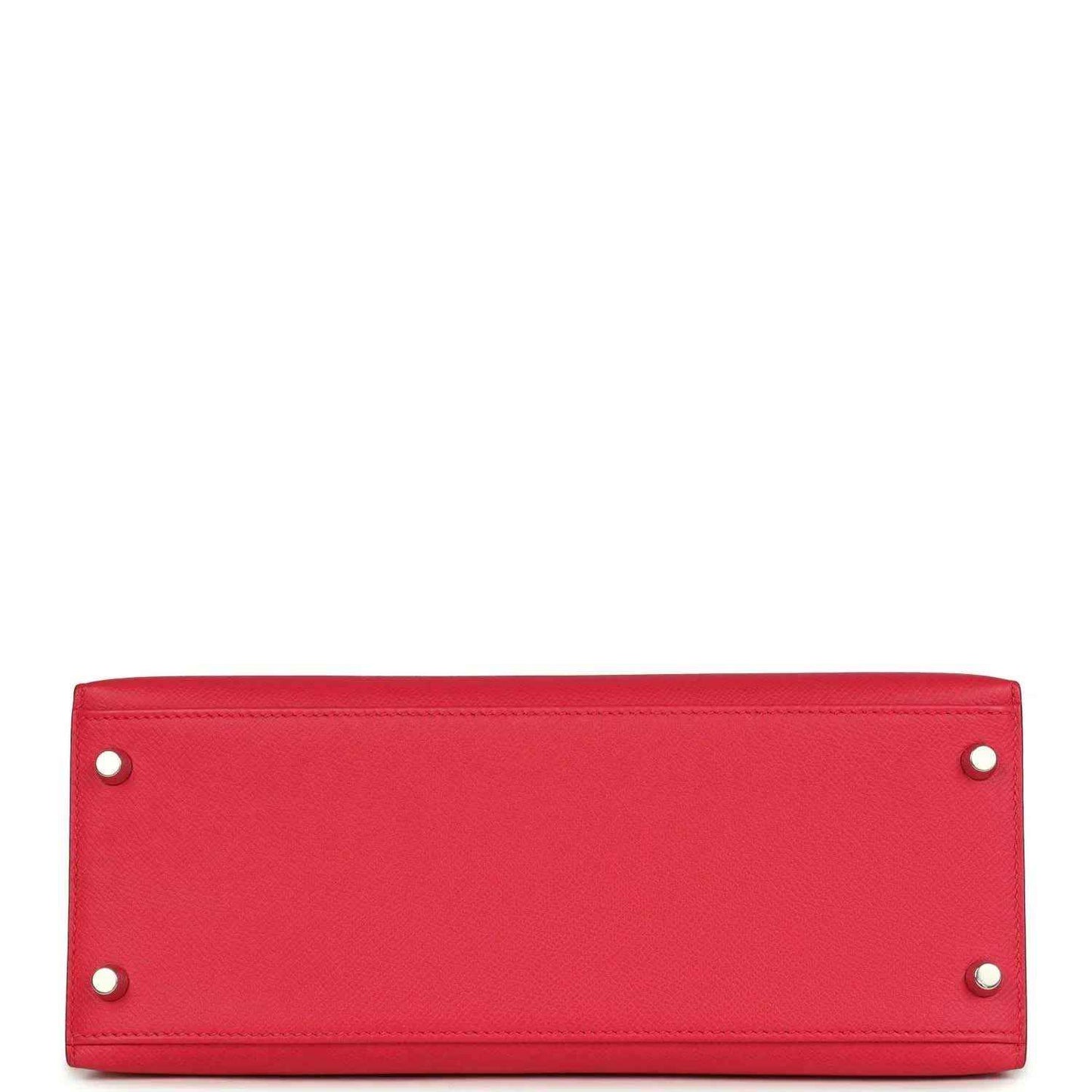 Red leather handbag panel with two metal studs along top edge.