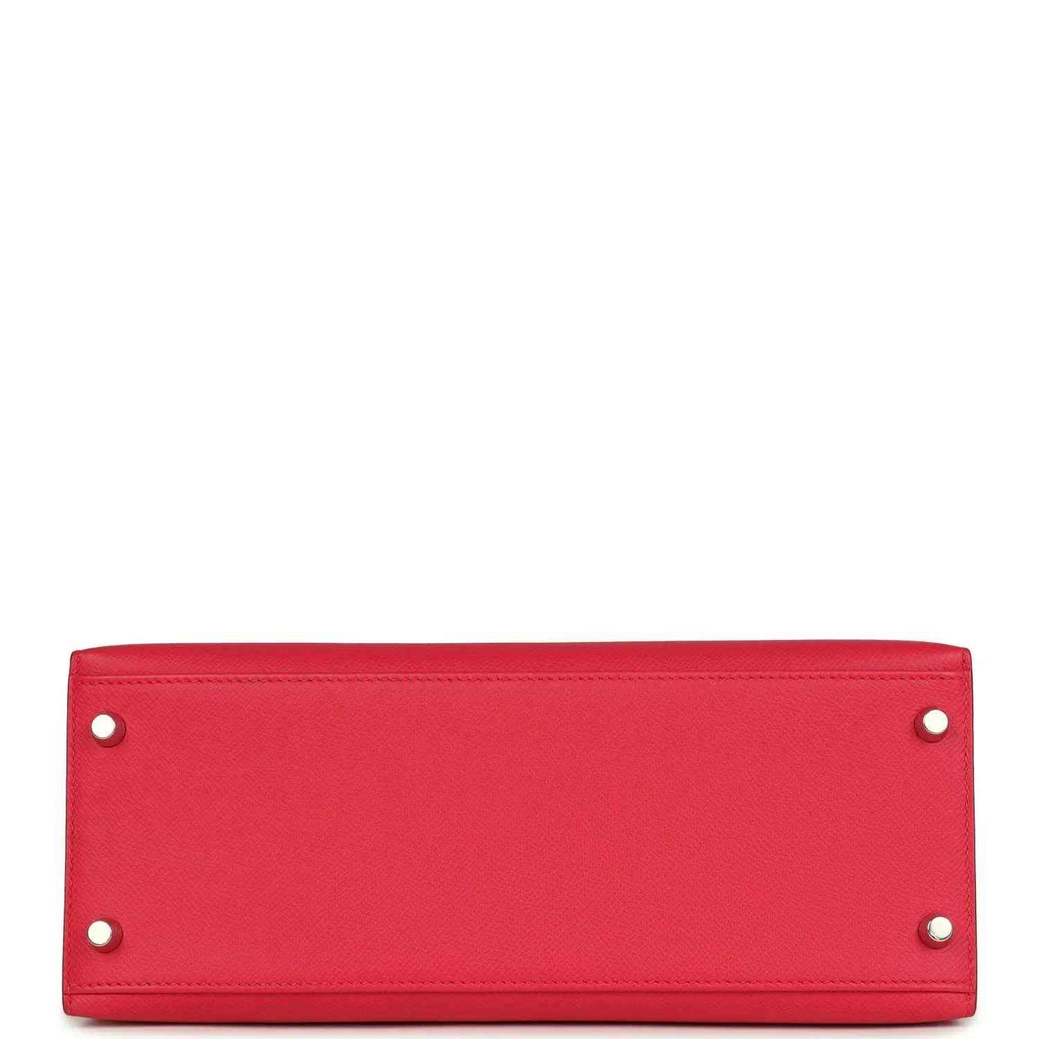 Red leather handbag panel with two metal studs along top edge.