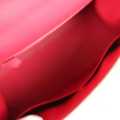 Red leather-lined handbag interior with textured grain and curved seam.