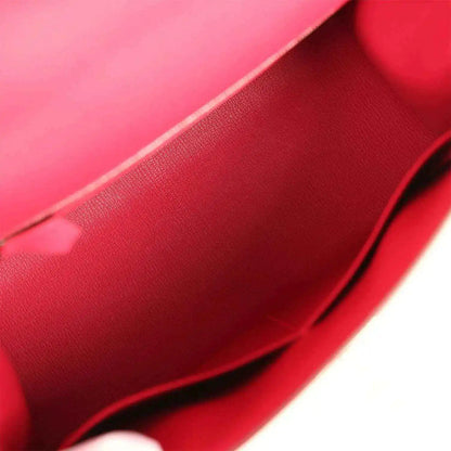 Red leather-lined handbag interior with textured grain and curved seam.
