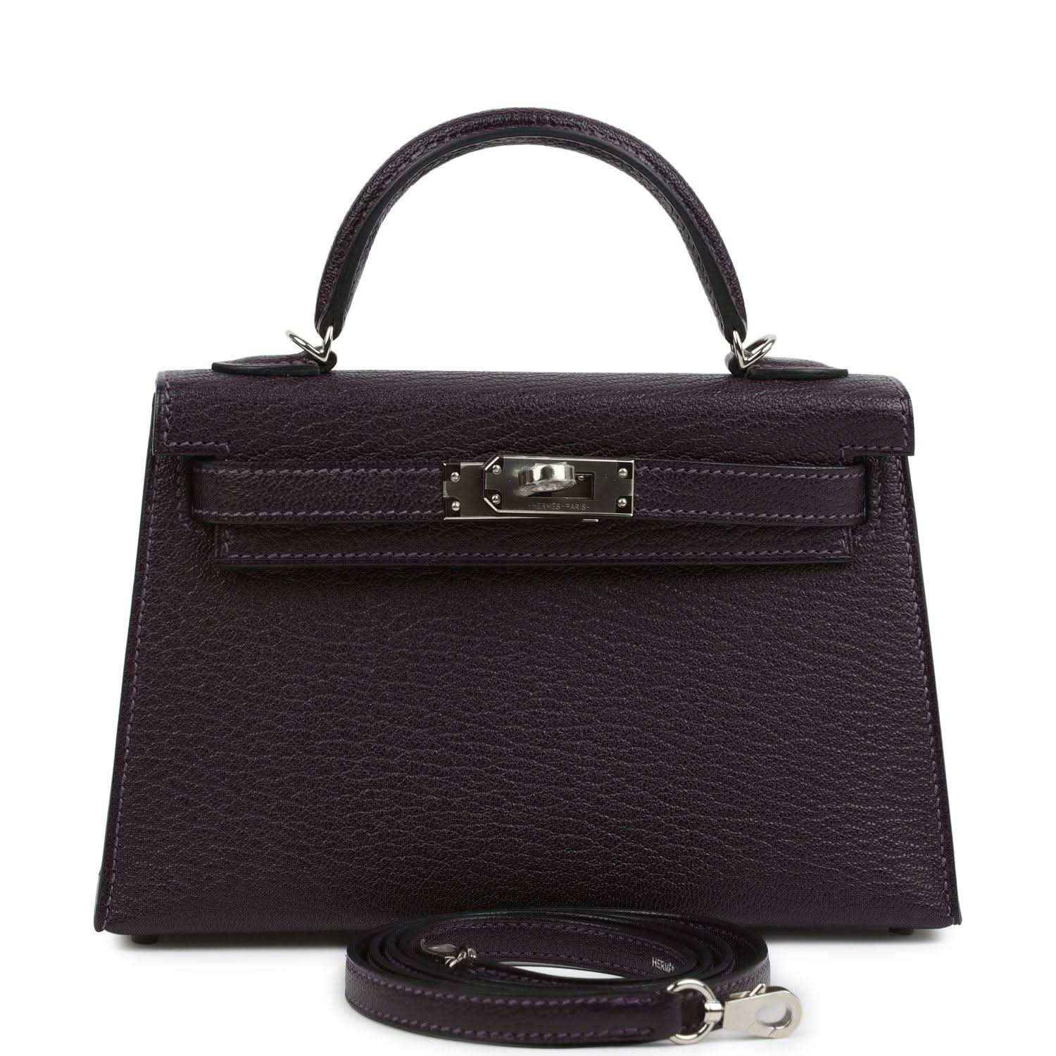 Purple leather handbag with top handle, front flap and metal clasp, detachable strap.