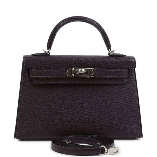 Purple leather handbag with top handle, front flap and metal clasp, detachable strap.