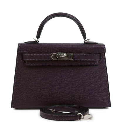 Purple leather handbag with top handle, front flap and metal clasp, detachable strap.