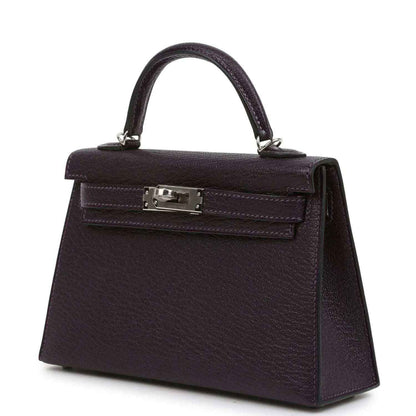 Purple leather handbag with top handle, front flap and metal clasp hardware.
