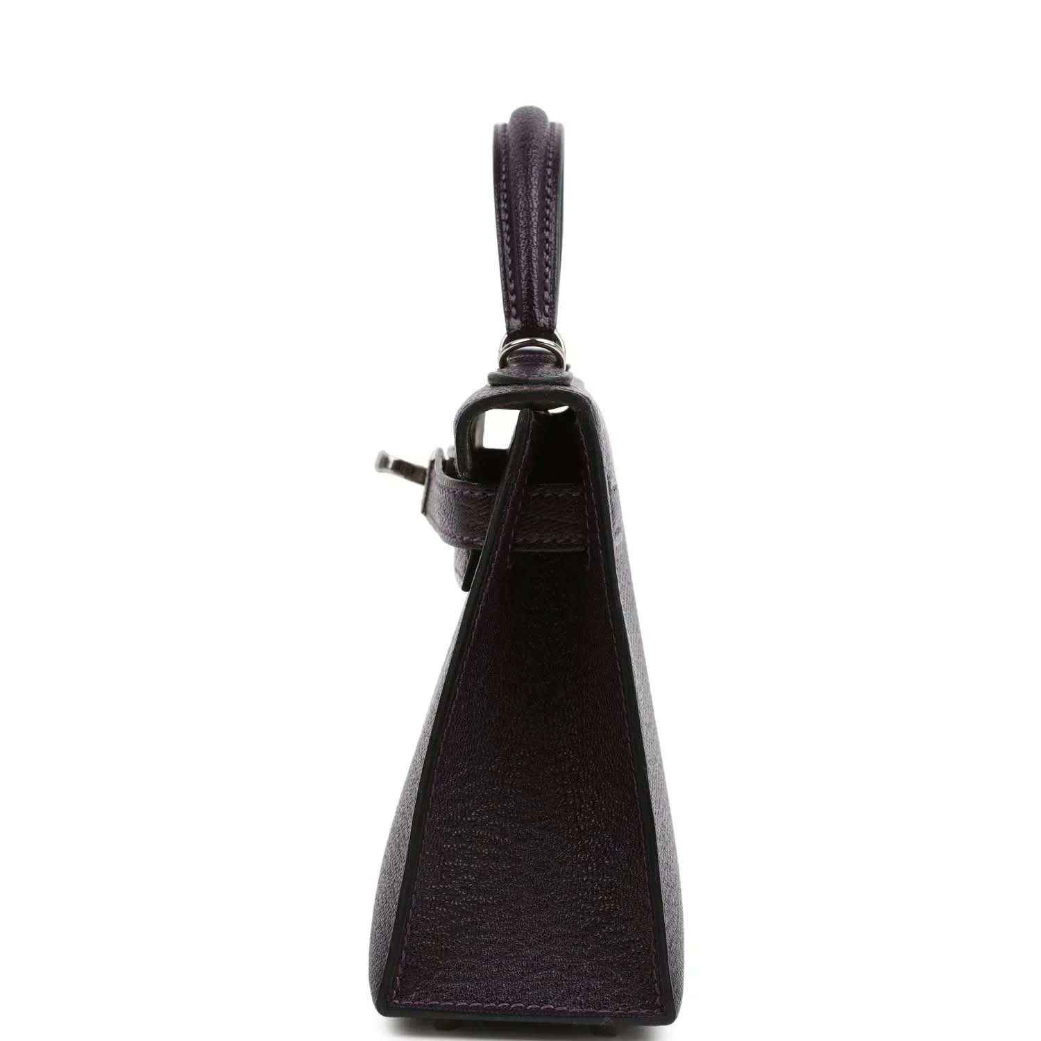 Purple leather handbag with top handle, side profile and leather strap attachment.