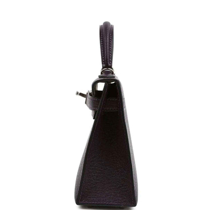 Purple leather handbag with top handle, side profile and leather strap attachment.